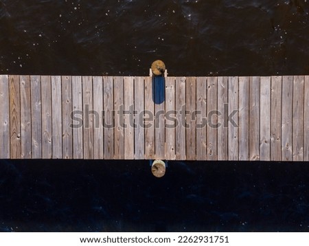 Top view of a wooden pier with two pillars on the side against the brown water surface- Navarre, FL. Horizontal wooden pier above the water.