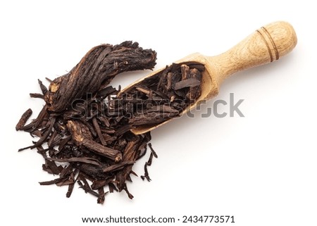 Top view of a wooden scoop filled with Organic Alkanet or Ratan Jot (Alkanna tinctoria) roots. Isolated on a white background.