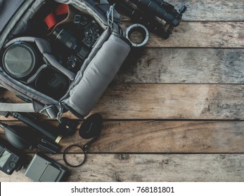 top view of work space photographer with digital camera in camera bag, flash, battery charger, cleaning kit, tripod, memory card, and camera accessory on wooden background