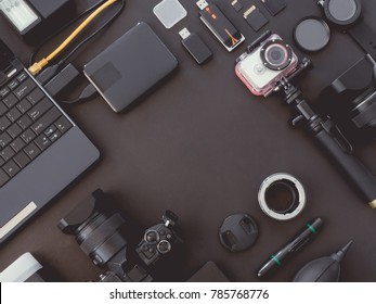 top view of work space photographer with digital camera, flash, camera cleaning kit, memory card, external harddisk, usb card reader and camera accessory on black background with copy space