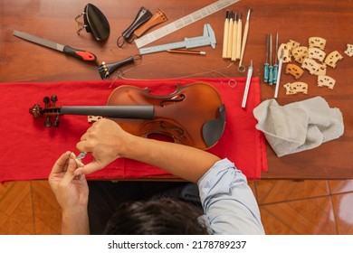 Top View Of A Worker In A Musical Instrument Repair Workshop Repairing A Violin