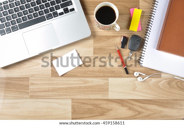 Top view of the working desk of a businessman\
with blank business card with laptop keyboard, black tea, car key,\
pen drive and other office articles. The blank card is ready to add\
contact details.