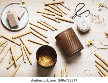 Top view of workplace with two old empty rusty food cans, bamboo stakes, air dry clay, string, scissors. Create a DIY bug hotel for garden. Kids craft and helping wild animals concept.