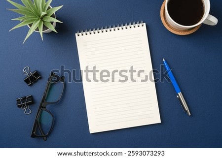 Top view of a workspace with a blank notebook, pen, glasses, coffee, and plant