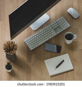 Top view of workspace with documents and gadgets placed near cup of coffee and office stationery on table