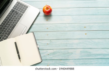 top view of a workspace with laptop computer idea notebook and pen, with a red apple on a blue vintage wooden table. Business concept.

 - Powered by Shutterstock