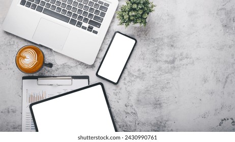 A top view of a workspace with modern tech gadgets including a laptop, tablet, smartphone, and a cup of coffee on a marble surface.