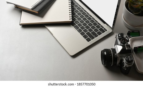 Top view of worktable with laptop, camera, notebooks and copy space in office room