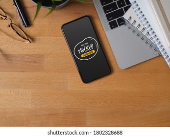 Top view of worktable with mock up smartphone, laptop, stationer, glasses and copy space 
