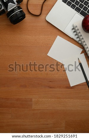Top view of worktable with stationery, camera, laptop and copy space in home office