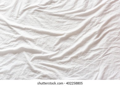 Top View Of Wrinkles On An Unmade / Untidy White Bed Sheet In A Bedroom After A Long Night Sleep And Waking Up In The Morning. A Blank / Empty Space That Can Be Used For Abstract Texture Background.
