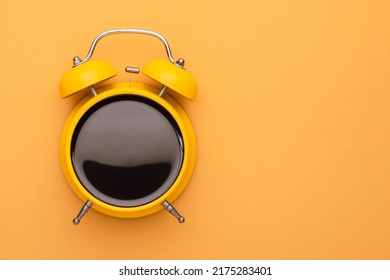 Top view yellow alarm clock with black coffee texture in the middle on bright color background