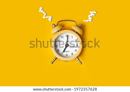 Top view of the yellow alarm clock on the yellow background with a free space for text. Getting up early in the morning. Wake up with a great mood