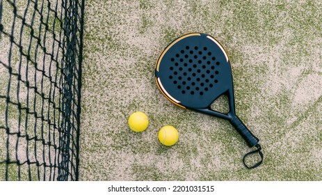 Top view of yellow balls on floor near of padel tennis racket in green court outdoors with natural lighting. Paddle is a racquet game. Professional sport concept