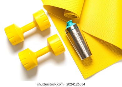 Top View Of Yellow Dumbbells And Protein Shaker On The Fitness Mat