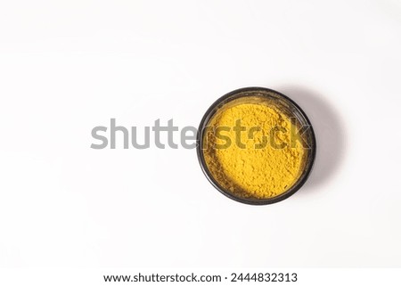 Top view of yellow holi powder in plastic box on white background for Indian festival Holi. Space for text.