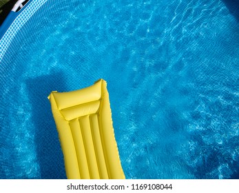 Top View Of A Yellow Inflatable Mattress In An Above Ground Private Backyard Swimming Pool