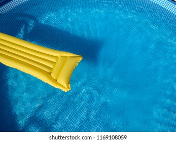 Top View Of A Yellow Inflatable Mattress In An Above Ground Private Backyard Swimming Pool