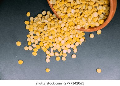 Top view of yellow split chickpeas or chana dal in a wooden bowl on a dark grey background healthy food ingredients, proteinrich pulses, and legumes
