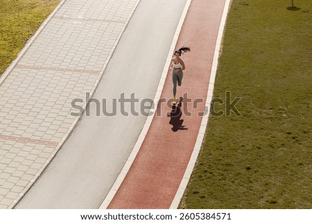 Top view of young active metropolitan athlete in motion running fast on running track on a city street.