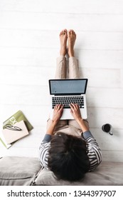 Top View Of A Young Afro American Woman Sitting At A Couch At Home, Using Laptop Computer, Drinking Coffee