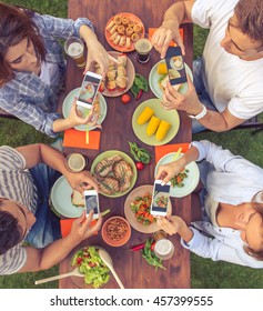 Top View Of Young Beautiful People Taking Photos Of Their Food While Sitting At The Table And Having Picnic Outdoors