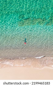 Top View. Young Beautiful Woman In Red Hat Standing And Sunbathe In Sea Water. Drone, Copter Photo. Summer Vacation. View From Above. 