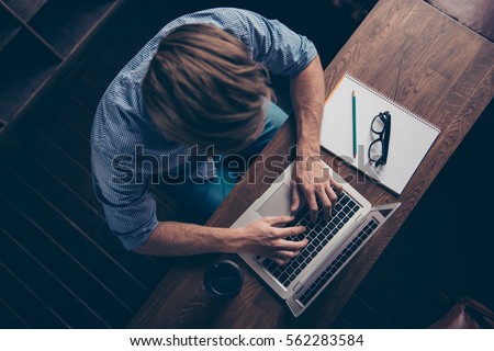 Top view of young busy worker typing on laptop