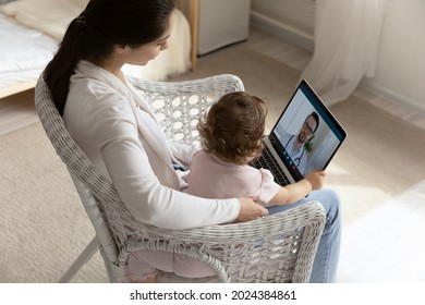 Top View Of Young Caucasian Mother With Baby Daughter Speak Talk On Video Call With Male Doctor On Computer. Caring Mom With Toddler Child Have Webcam Online Consultation With Pediatrician.