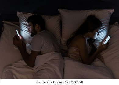 top view of young couple lying in bed at night and using smartphones - Powered by Shutterstock