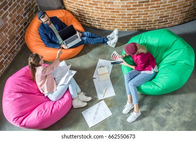 Top View Of Young Designers Or Architects Working While Sitting In Bean Bag Chairs