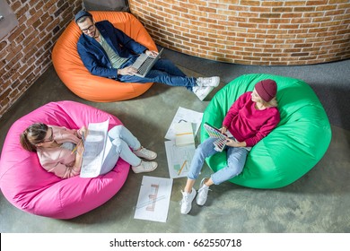 Top View Of Young Designers Or Architects Working While Sitting In Bean Bag Chairs