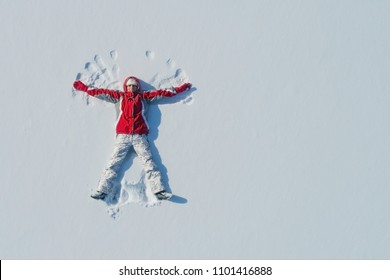 Top view of young girl is lying on the snow and making angel wings. Copy space. - Powered by Shutterstock