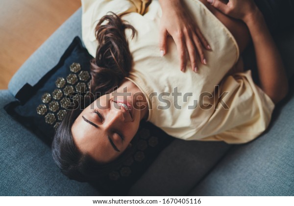 Top view of young happy beautiful woman\
relaxing with closed eyes on Massage Pillow ergonomic designed,\
fits perfectly behind neck and body contours of shoulder, Relax\
Wellness Healthy Lifestyle