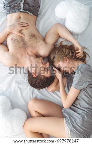 Young couple in love embracing lying over a bed