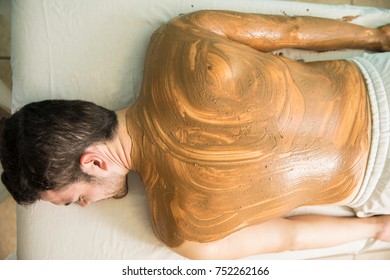 Top View Of A Young Man Falling Asleep And Enjoying A Mud Bath In A Health Spa