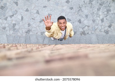 Top View Of Young Man Looking Up And His Arm Stretched