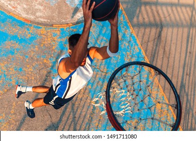 Top view of young man playing basketball outdoor. Slam dunk. - Powered by Shutterstock