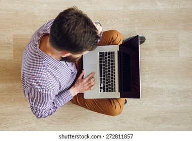 Top View Of Young Man Sitting On The Floor And Working With A Laptop