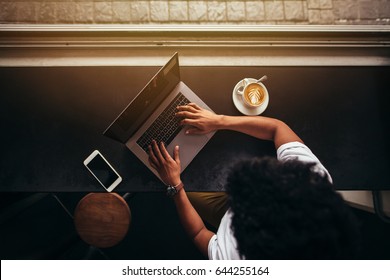 Top View Of Young Man Sitting At Cafe And Working On Laptop. Shot From Above Of Male Working On Laptop At Coffee Shop