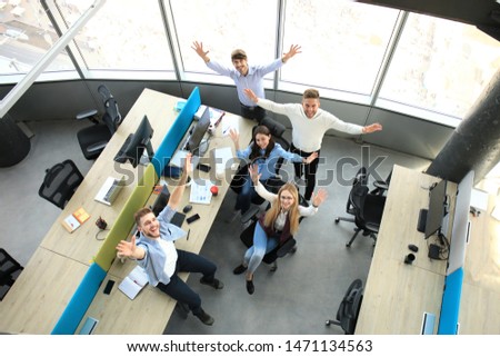 Top view of young modern colleagues in smart casual wear working together while spending time in the office.