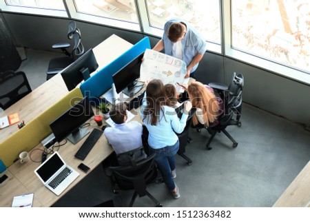 Top view of young modern colleagues in smart casual wear working together while spending time in the office.