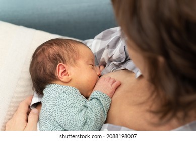 Top view of a young mother breastfeeding her newborn at home.
