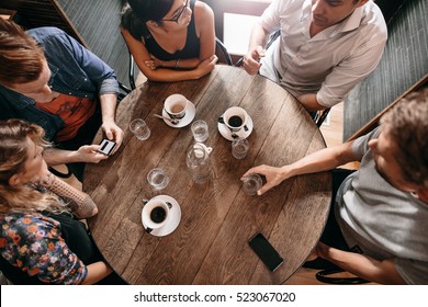 Top View Of Young People Sitting At Cafe With Cup Of Coffee On Table. Group Of Friends At Coffee Shop.