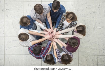 Top View Of Young People With Their Hands Together In A Circle.