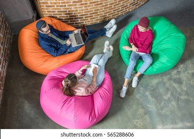 Top view of young stylish people chatting while sitting in bean bag chairs