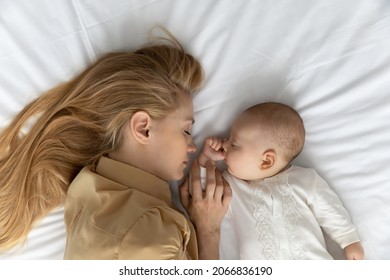 Top view young tired mother and baby sleeping on white bed sheet together, loving caring Caucasian mom with small newborn child infant fall asleep taking day nap, resting, motherhood concept