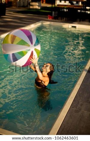 Top view at young woman with ball in the pool at sunny day