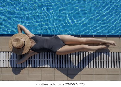 Top view of young woman enjoying day at the pool, laying down at the edge covering face with straw boater hat. Summer vacation concept.	 - Powered by Shutterstock