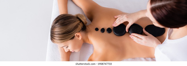 top view of young woman getting hot stone massage in spa salon, banner